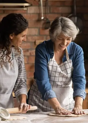 Two Tuscan women laughing while working pasta dough